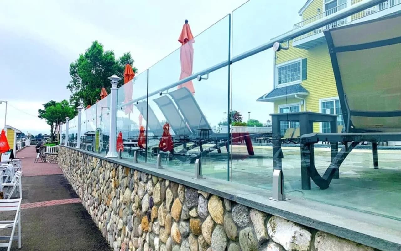 Frameless glass pool fence on stone wall at a coastal hotel — Fenced.ca